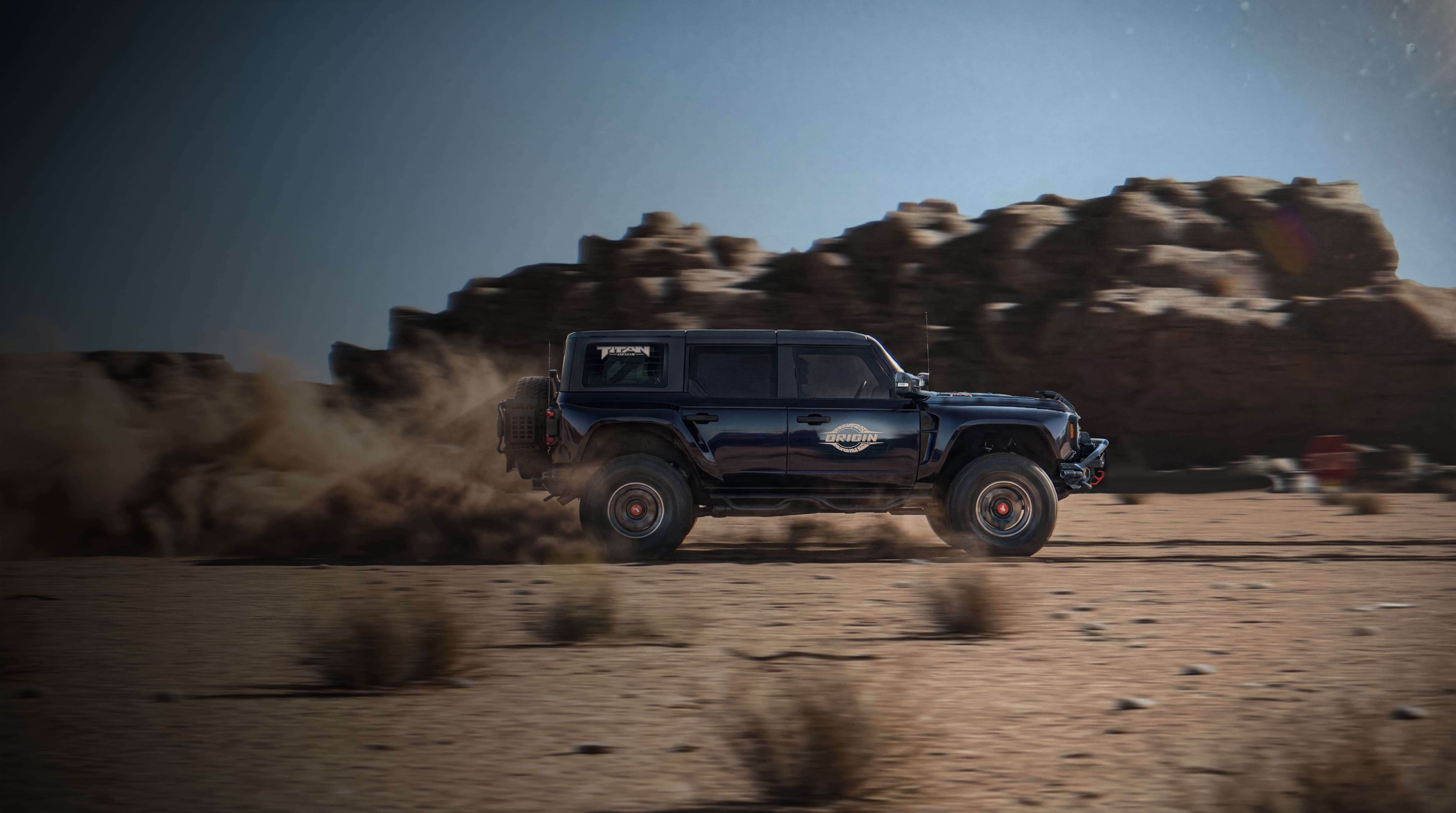 Red off-road SUV parked on sandy desert terrain under clear blue sky.